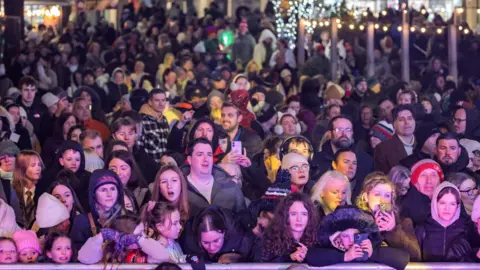 Sunderland City Council Thousands of people smile as they watch the festivities in Sunderland city centre. Several are taking pictures and videos on their mobile phones.
