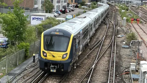 A South Western Railway train leaving a train station.