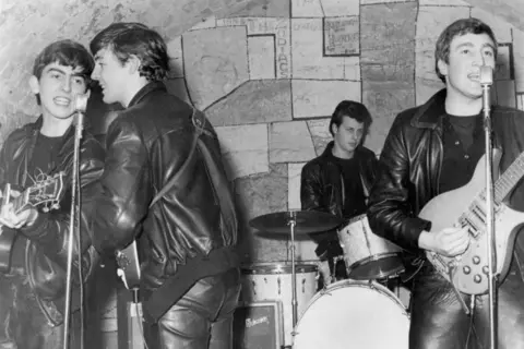 Getty Images An archival photo of The Beatles (George, Paul and John) with drummer Pete Best performing at The Cavern Club