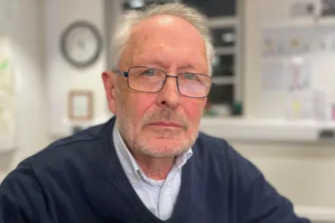 Image of man in glasses wearing a navy jumper