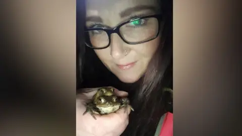 Milly Kennedy Milly Kennedy holding two toads in her hand while out on patrol. She is looking at the camera.