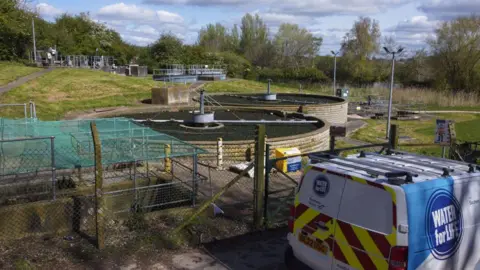 A van parked next to a water treatment works.