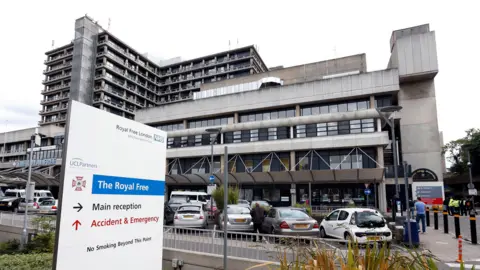 PA Media A general view of the exterior of the Royal Free Hospital, a concrete building with cars and a white and blue sign in front of it