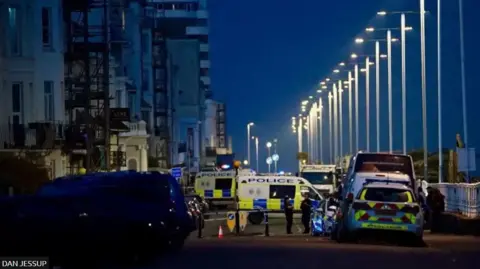 Police and emergency services cordoned off properties on a highway. 