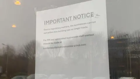 Mick Lunney/BBC A sheet of white paper taped to the inside of a glass door or window. The notice is printed in large text at the top with the heading “IMPORTANT NOTICE”, followed by smaller text explaining that, due to regulatory matters, the businesses operating from the building can no longer trade. The sign also provides an email address for staff from PM Law and associated businesses to contact.