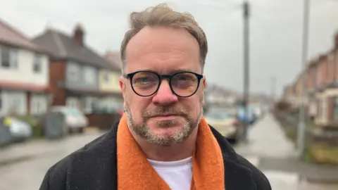 Man in orange scarf on road.
