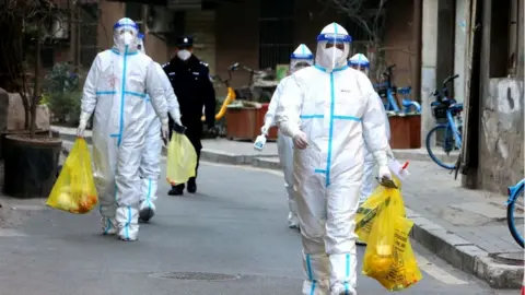 Getty Images Staff members in protective suits as they test people in Xi'an