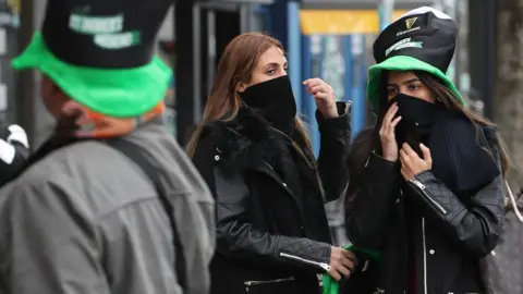 Niall Carson/PA Tourists wearing scarves over their mouths near O'Connell Street in Dublin on St Patrick's day