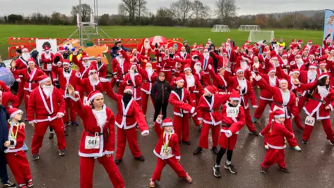 BBC People dressed in Santa costumes dancing