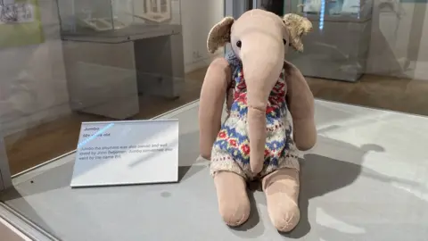 Oxfordshire Museum stuffed toy elephant wearing multicoloured dress