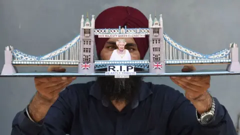 Getty Images Image shows man holding up paper tribute to the Queen