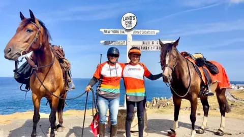 A picture of the pair of people and horses at the finish line, at Lands End.