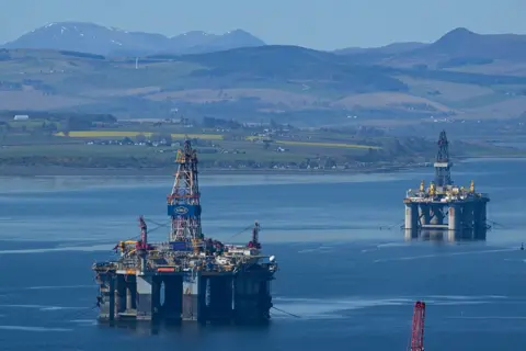 Getty Images Two oil platforms on the Cromarty Firth - a clear blue stretch of water with hills and snow-capped mountains in the background