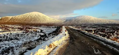 Victor Tregubov A snowy scene of a mountain with a road in the foreground