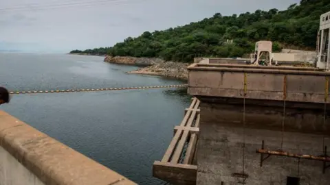 The Kariba dam seen from one of its ridges, overlooking the reservoir and green landscape in the distance