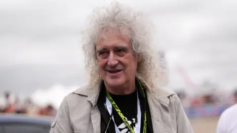 Sir Brian May, with wild white hair, arrives at the British Grand Prix at Silverstone 