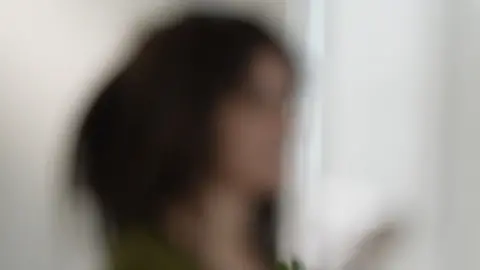 A heavily blurred image of a dark-haired woman looking to the side