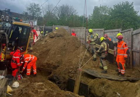 Crews work to rescue man from trench
