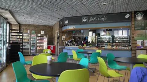The cafe with green and teal chairs with a blue counter in the background.