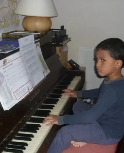 Handout A young Kamal is playing the piano. He is wearing a navy tracksuit. 