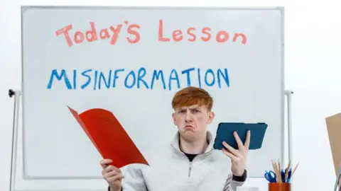 Internet Matters/Tesco Angry Ginge posing looking confused sat at a school desk in front of a whiteboard reading: 'Today's lesson: MISINFORMATION'.
