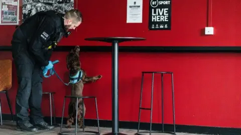 Northamptonshire Police A brown spaniel and a police officer training in a bar area at Sixfields Stadium
