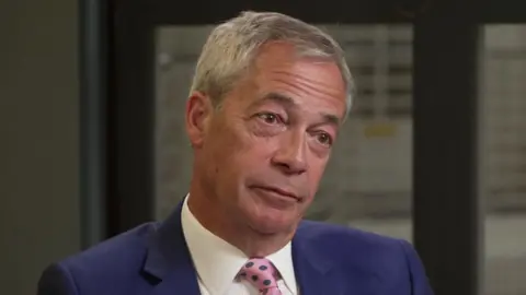 BBC Nigel Farage being interviewed in a blue suit and pink spotted tie