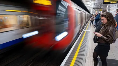 Getty Images A blurred image of a Tube train pulling into a platform as people wait for its arrival. 