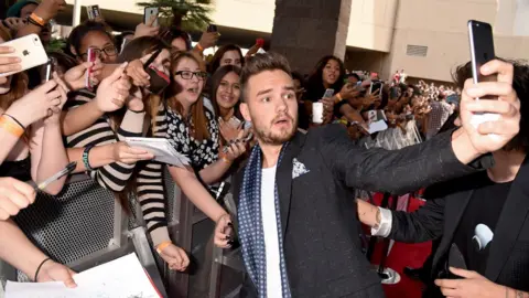 Getty Images Liam Payne takes a selfie with a large group of fans outside an awards ceremony in 2015