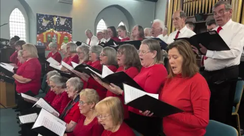 A group of choir singers all wearing red