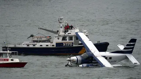 Getty Images Emergency services on a boat respond to a crashed seaplane in the East River on 5 July 2026 in New York City.