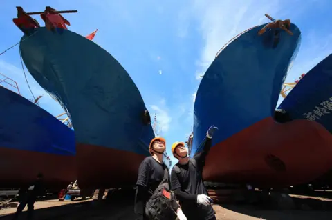 Zhang Peijian/VCG via Getty Images Two surveyors inspect ships