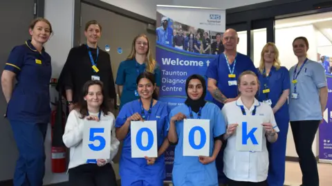 Staff holding up sign celebrating half a million patients