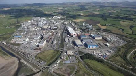 An aerial image of Sellafield. The large site, which looks like an industrial estate with several buildings, roads and car parks, is surrounded by green fields.