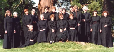 Diocese of Portsmouth Eighteen women who had been ordained as priests feature as a group stood in front of two large trees
