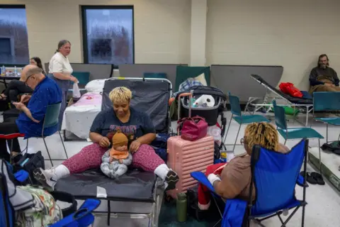 Kathleen Flynn/Reuters Lindsay Smith, her four-month-old son Maze Crawford and mother Dieonne Smith wait for the arrival of Hurricane Helene at Lincoln High School, which has opened as an emergency shelter in Tallahassee, Florida