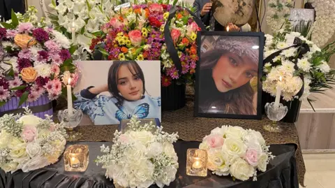 Tribute display featuring photographs of Ghazal Damarcheli surrounded by candles and flowers