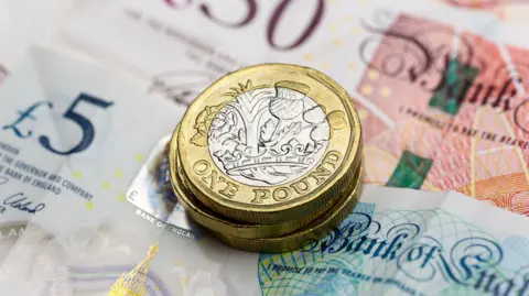 Three pound coins placed on top of British bank notes.