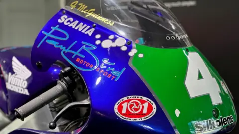 The front of the bike, which is metallic blue with the number four on a green plate.