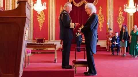 PA Media King Charles chats with Brian May after knighting him at Buckingham Palace