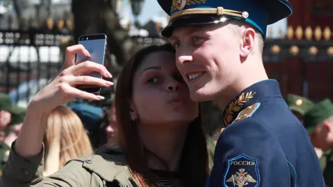Tass/Getty A woman takes a selfie with a Russia soldier