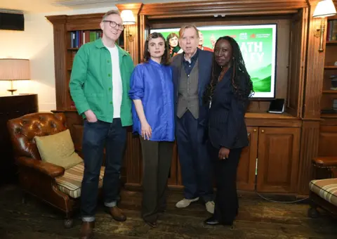 Lucy North/PA Wire Paul Doolan, Gwyneth Keyworth, Timothy Spall and Madeline Addy stand in a line in front of a screen with a promo image of Death Valley