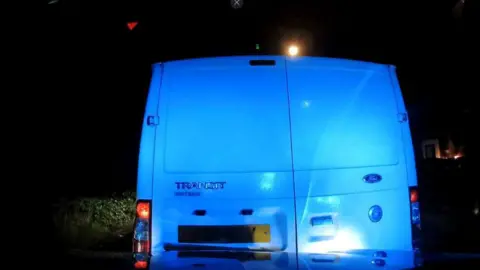Nottinghamshire Police The back of a Ford Transit van illuminated by blue lights at night.