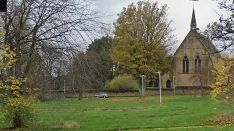 An open stretch of grassy land next to Christ Church in Felling on a cloudy day.