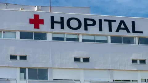 Facade of a French hospital with the red cross and French word Hopital
