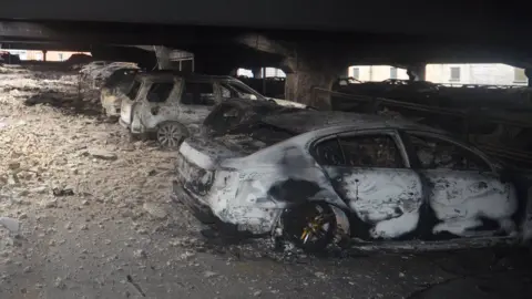 Burnt out cars in a stone car park