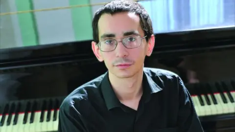 Sverdlovsk Local History Museum Pavel Kushnir sits in front of a piano