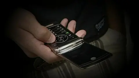 BBC Close up of hand inputting data into a mobile phone