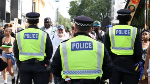 A general view of the back of three Metropolitan Police officers at Notting Hill Carnival. 