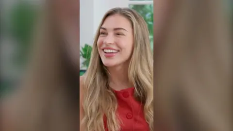 Zara McDermott has long blonde hair and is wearing a red top.